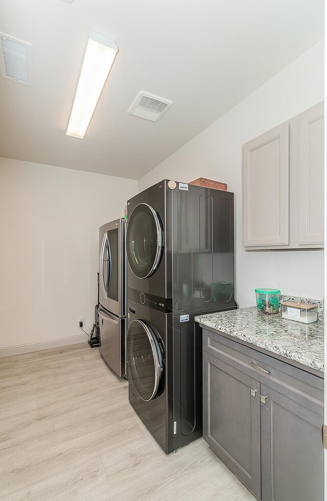1523 N Ryan Ave, Clovis, CA 93619 - laundry room with stacked washer and clothes dryer, cabinet space, light wood finished floors, and baseboards