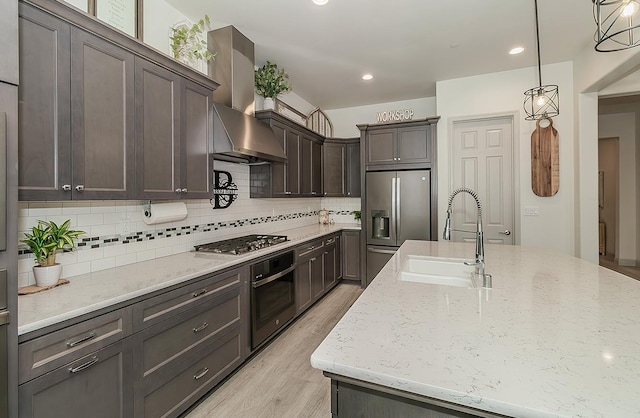 1523 N Ryan Ave, Clovis, CA 93619 - kitchen with appliances with stainless steel finishes, a sink, wall chimney range hood, light wood-style flooring, and light stone counters