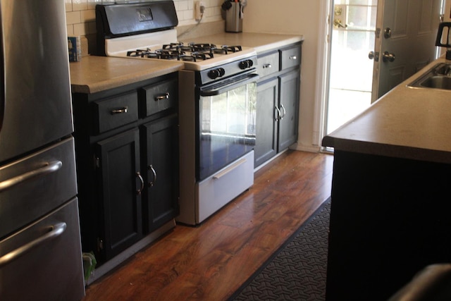 4657 E Hamilton Ave, Fresno, CA 93702 - kitchen featuring gas range oven, freestanding refrigerator, decorative backsplash, and dark wood finished floors