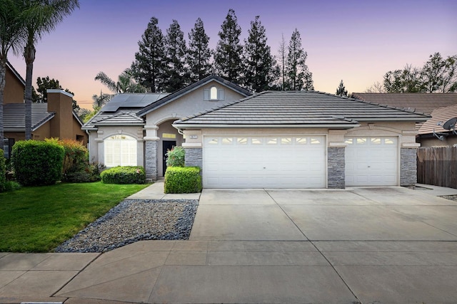 2871 E Ryan Ln, Fresno, CA 93720 - view of front of house with an attached garage, stone siding, concrete driveway, a lawn, and stucco siding