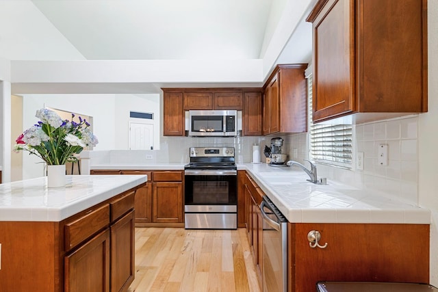 2871 E Ryan Ln, Fresno, CA 93720 - kitchen featuring stainless steel appliances, a sink, light wood-style flooring, backsplash, and brown cabinets