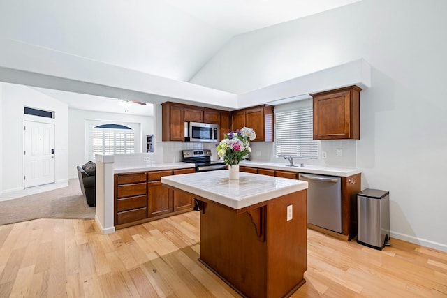 2871 E Ryan Ln, Fresno, CA 93720 - kitchen with stainless steel appliances, a sink, light wood-style flooring, decorative backsplash, and a kitchen island