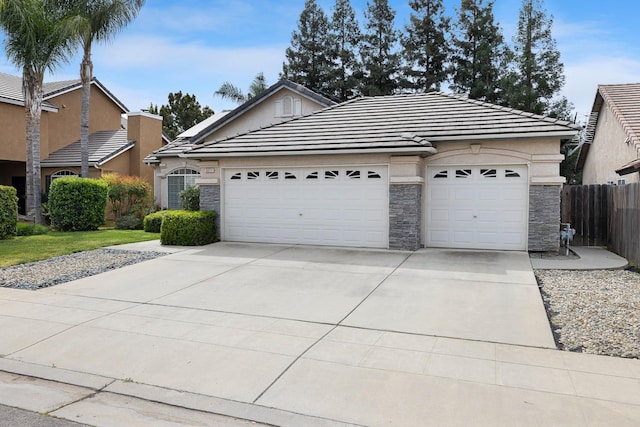 2871 E Ryan Ln, Fresno, CA 93720 - view of front of home with stone siding, a garage, a tiled roof, and driveway