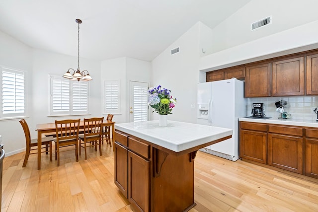 2871 E Ryan Ln, Fresno, CA 93720 - kitchen featuring white fridge with ice dispenser, a chandelier, light wood-type flooring, decorative light fixtures, and decorative backsplash