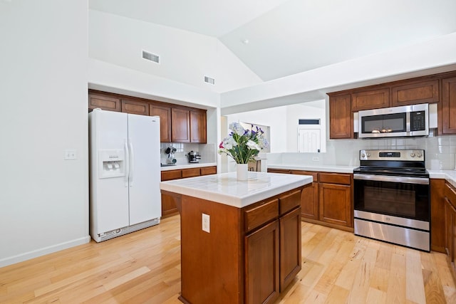 2871 E Ryan Ln, Fresno, CA 93720 - kitchen with appliances with stainless steel finishes, light countertops, light wood-style floors, decorative backsplash, and lofted ceiling