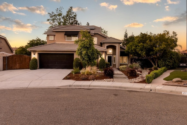 2176 E Pinehurst Ave, Fresno, CA 93730 - mediterranean / spanish house featuring driveway, a tiled roof, stucco siding, a gate, and a garage