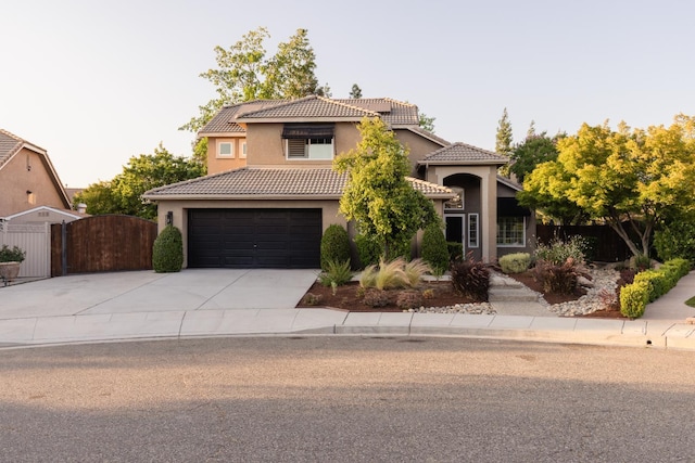 2176 E Pinehurst Ave, Fresno, CA 93730 - mediterranean / spanish house featuring concrete driveway, stucco siding, a tiled roof, a garage, and a gate