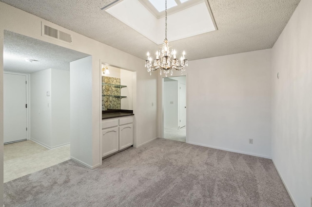 1709 W Calimyrna Ave Unit B, Fresno, CA 93711 - unfurnished dining area featuring a textured ceiling, a chandelier, light carpet, a skylight, and baseboards