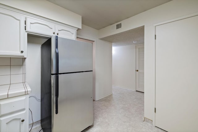 1709 W Calimyrna Ave Unit B, Fresno, CA 93711 - kitchen featuring freestanding refrigerator, tile counters, white cabinets, backsplash, and light floors