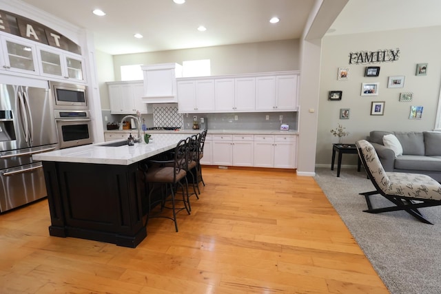 2143 Everglade Ave, Clovis, CA 93619 - kitchen with appliances with stainless steel finishes, a sink, tasteful backsplash, white cabinets, and a breakfast bar area