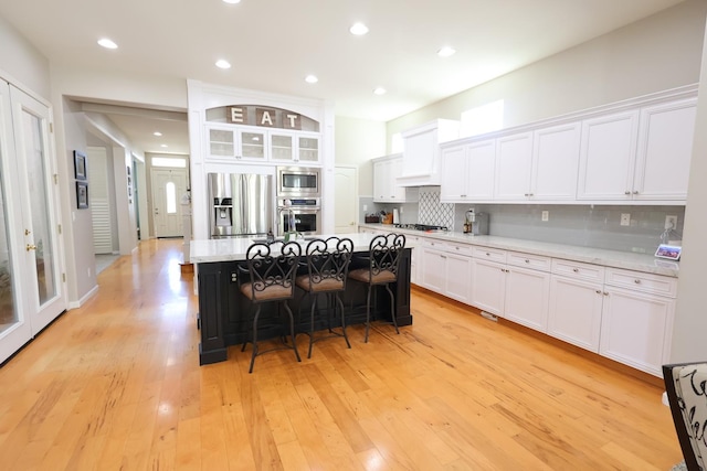 2143 Everglade Ave, Clovis, CA 93619 - kitchen featuring appliances with stainless steel finishes, white cabinetry, a breakfast bar, decorative backsplash, and recessed lighting