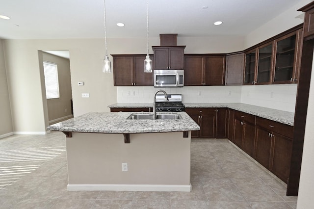 3368 Monterosa Ln, Clovis, CA 93619 - kitchen featuring stainless steel microwave, a sink, gas range oven, decorative backsplash, and a center island with sink