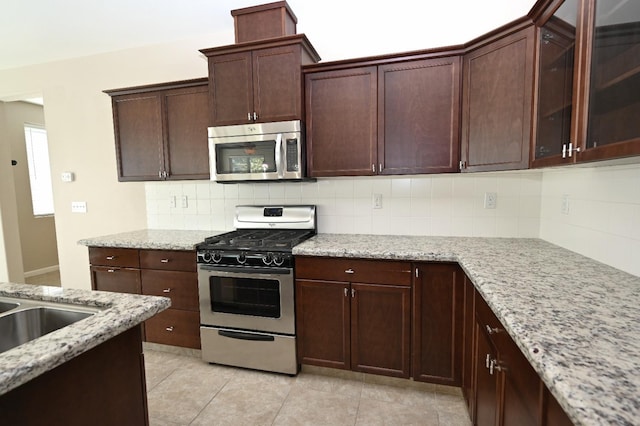 3368 Monterosa Ln, Clovis, CA 93619 - kitchen featuring stainless steel appliances, decorative backsplash, light tile patterned floors, light stone countertops, and dark brown cabinetry