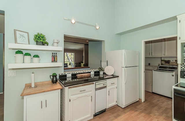 38830 Littlefield Rd, Shaver Lake, CA 93664 - kitchen featuring washing machine and clothes dryer, freestanding refrigerator, a towering ceiling, light wood-style floors, and white cabinets