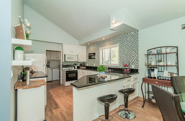 38830 Littlefield Rd, Shaver Lake, CA 93664 - kitchen featuring white appliances, separate washer and dryer, a peninsula, light wood-type flooring, and vaulted ceiling