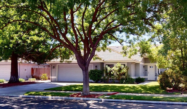 1604 W Central Ave, Madera, CA 93637 - view of property hidden behind natural elements with stucco siding, driveway, a garage, a tile roof, and a front yard