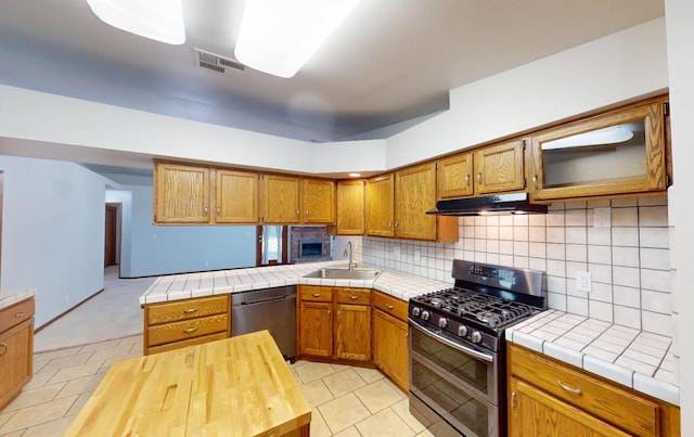 1604 W Central Ave, Madera, CA 93637 - kitchen featuring stainless steel appliances, under cabinet range hood, brown cabinets, and light tile patterned flooring
