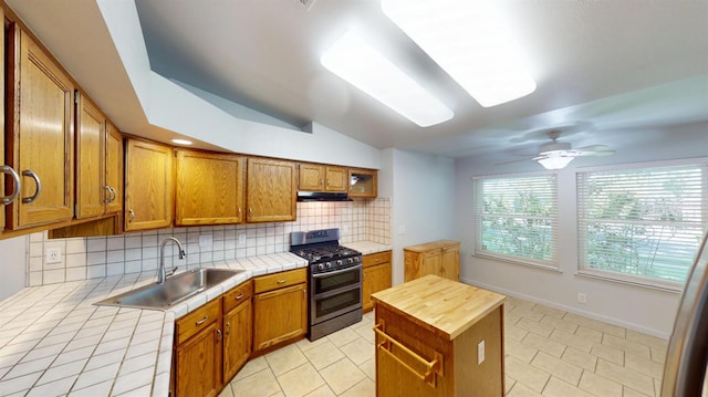 1604 W Central Ave, Madera, CA 93637 - kitchen with gas stove, tile counters, under cabinet range hood, light tile patterned floors, and decorative backsplash
