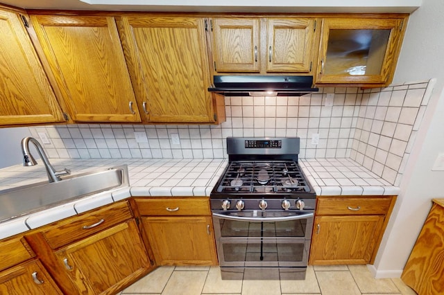 1604 W Central Ave, Madera, CA 93637 - kitchen featuring gas stove, under cabinet range hood, light tile patterned floors, and tile counters