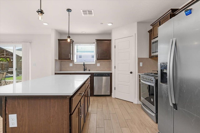 2520 S Spruce St, Visalia, CA 93292 - kitchen featuring appliances with stainless steel finishes, light wood-style flooring, dark brown cabinetry, decorative backsplash, and a sink