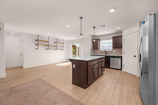 2520 S Spruce St, Visalia, CA 93292 - kitchen with stainless steel appliances, light wood-type flooring, dark brown cabinetry, a kitchen island, and tasteful backsplash