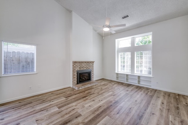1892 E Goshen Ave, Fresno, CA 93720 - unfurnished living room with wood finished floors, a ceiling fan, high vaulted ceiling, a fireplace, and a textured ceiling