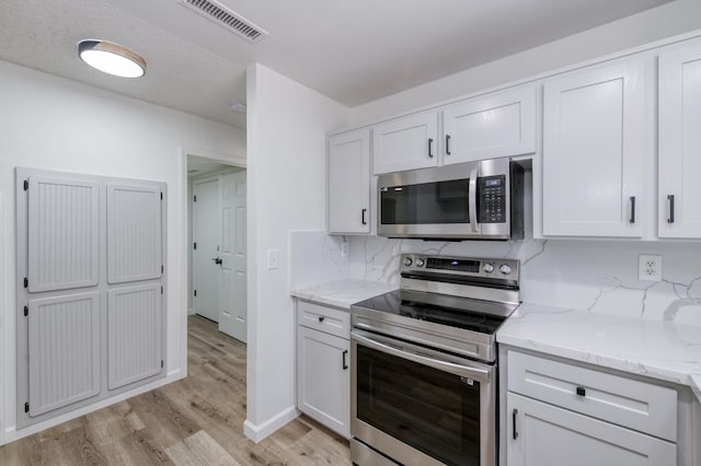 1892 E Goshen Ave, Fresno, CA 93720 - kitchen with stainless steel appliances, light wood finished floors, white cabinets, light stone countertops, and decorative backsplash