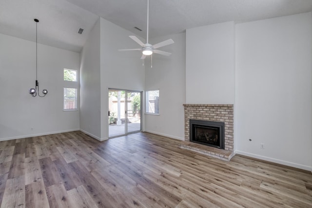 1892 E Goshen Ave, Fresno, CA 93720 - unfurnished living room with high vaulted ceiling, a brick fireplace, wood finished floors, and baseboards