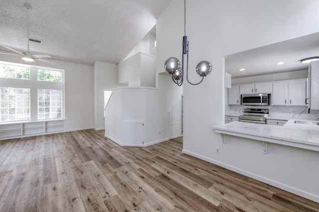 1892 E Goshen Ave, Fresno, CA 93720 - unfurnished living room featuring a ceiling fan, light wood-style floors, high vaulted ceiling, a sink, and baseboards