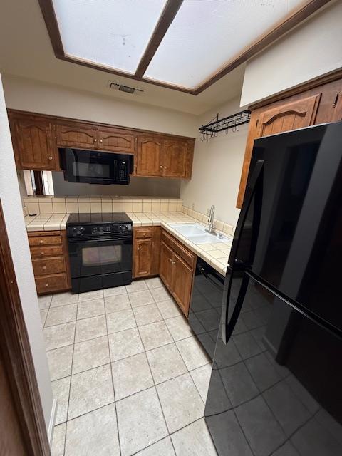 5749 N Monte Ave Unit 2, Fresno, CA 93711 - kitchen with tile counters, black appliances, light tile patterned floors, and a sink