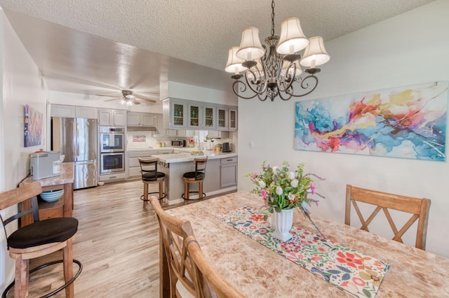 2934 N 8th St, Fresno, CA 93703 - dining area with light wood-style floors, a chandelier, a textured ceiling, and ceiling fan