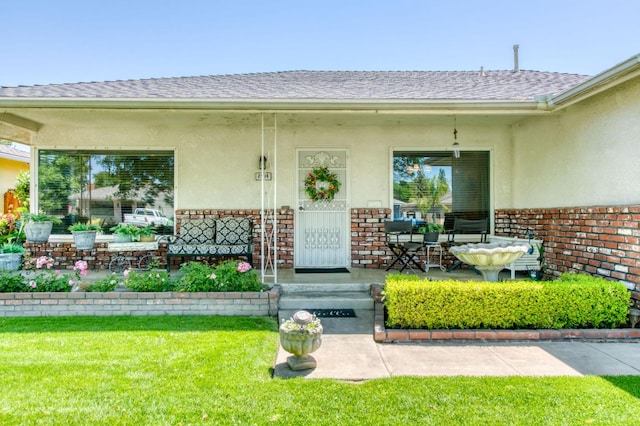 2934 N 8th St, Fresno, CA 93703 - entrance to property featuring stucco siding, covered porch, roof with shingles, a yard, and brick siding