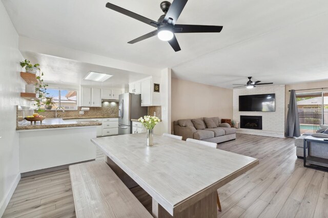 2051 E Fremont, Fresno, CA 93710 - dining area with a ceiling fan, light wood-style floors, a fireplace, and baseboards