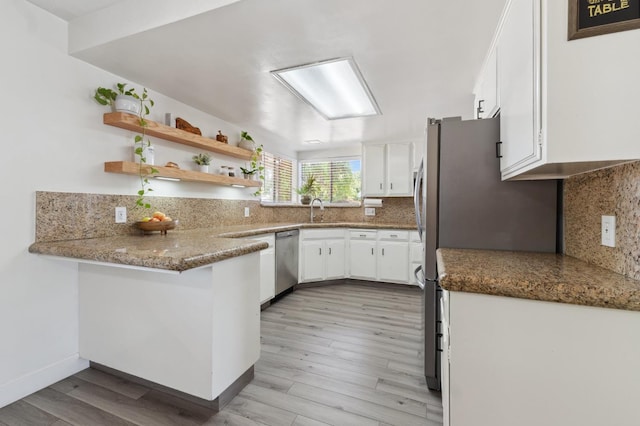 2051 E Fremont, Fresno, CA 93710 - kitchen with appliances with stainless steel finishes, white cabinetry, backsplash, light wood finished floors, and a peninsula