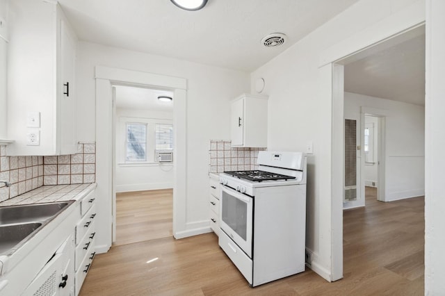 1593 N Glenn Ave, Fresno, CA 93728 - kitchen with white gas range oven, white cabinets, tasteful backsplash, and light wood-style floors