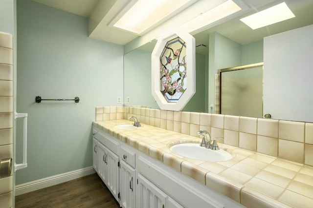 2081 Santa Ana Ave, Clovis, CA 93611 - full bath with a skylight, double vanity, wood finished floors, baseboards, and a stall shower
