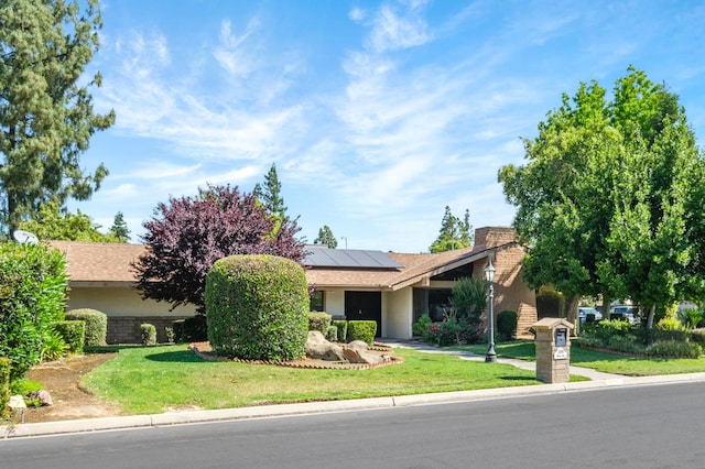 2081 Santa Ana Ave, Clovis, CA 93611 - view of property hidden behind natural elements with roof mounted solar panels, a front yard, and stucco siding