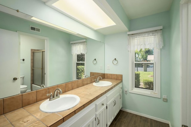 2081 Santa Ana Ave, Clovis, CA 93611 - full bathroom featuring double vanity, toilet, a shower with door, wood finished floors, and baseboards