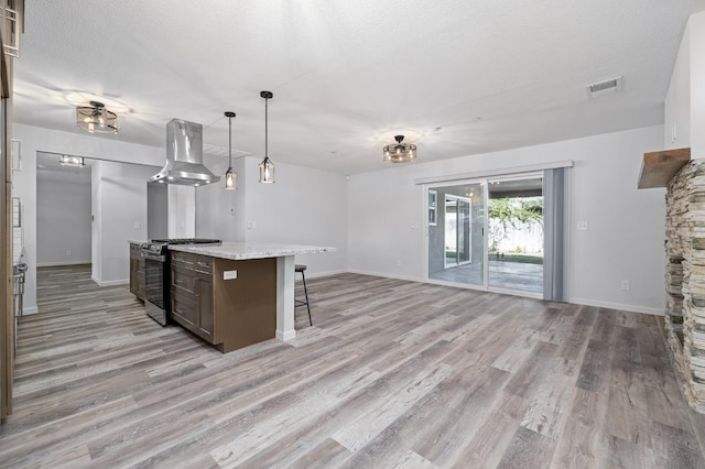 3752 N Augusta St, Fresno, CA 93726 - kitchen featuring gas range, island range hood, a kitchen breakfast bar, light wood-style flooring, and baseboards