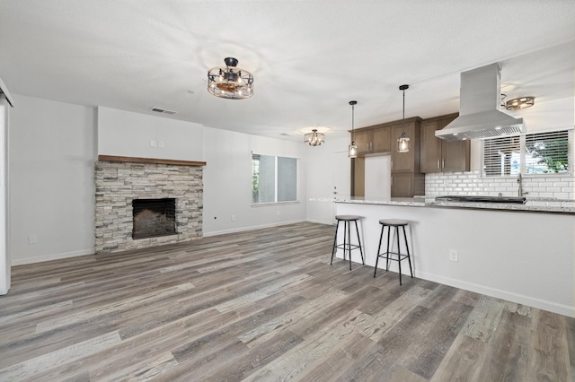 3752 N Augusta St, Fresno, CA 93726 - kitchen with island exhaust hood, light wood finished floors, a kitchen breakfast bar, decorative backsplash, and light stone counters