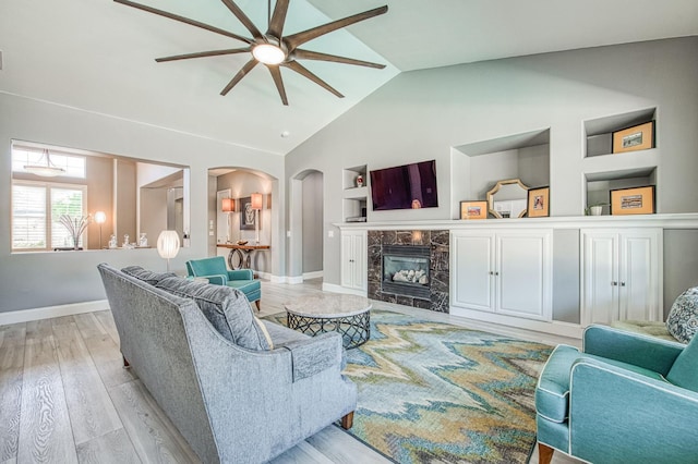 3081 Serena Ave, Clovis, CA 93619 - living room with a ceiling fan, arched walkways, built in shelves, light wood finished floors, and baseboards
