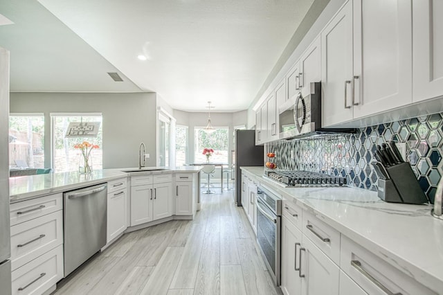 3081 Serena Ave, Clovis, CA 93619 - kitchen with appliances with stainless steel finishes, a sink, white cabinetry, backsplash, and light wood finished floors