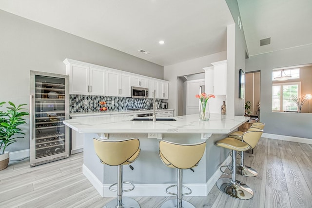 3081 Serena Ave, Clovis, CA 93619 - kitchen featuring beverage cooler, stainless steel appliances, tasteful backsplash, white cabinets, and a kitchen bar