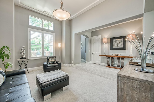 3081 Serena Ave, Clovis, CA 93619 - living area featuring arched walkways, a high ceiling, light carpet, and baseboards