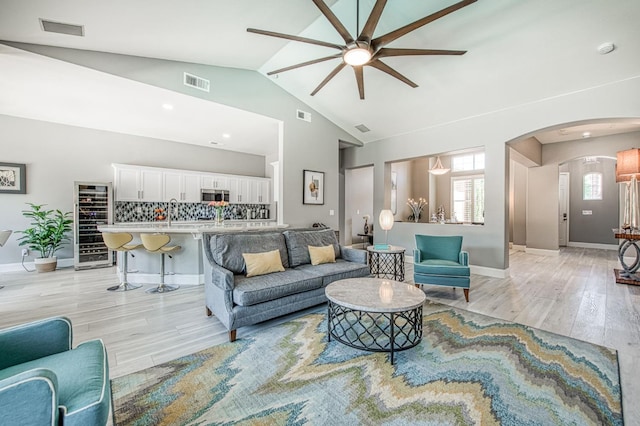 3081 Serena Ave, Clovis, CA 93619 - living room featuring a ceiling fan, wine cooler, arched walkways, light wood finished floors, and lofted ceiling