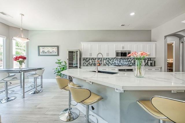 3081 Serena Ave, Clovis, CA 93619 - kitchen featuring stainless steel microwave, white cabinetry, a breakfast bar area, a sink, and recessed lighting
