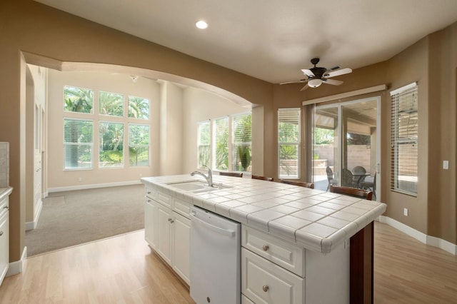 1698 E Wallington Ln, Fresno, CA 93730 - kitchen with white dishwasher, a sink, tile counters, a ceiling fan, and light wood-style floors
