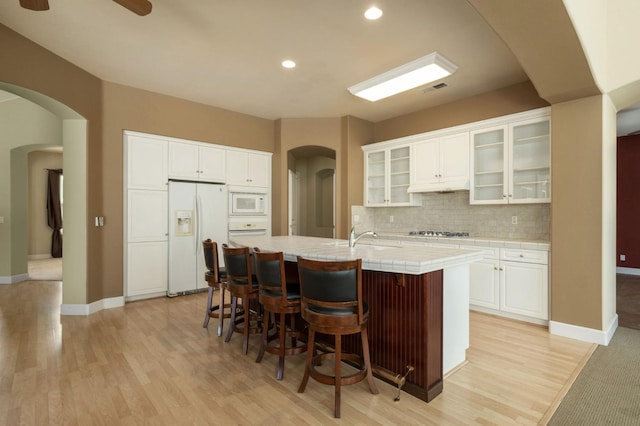 1698 E Wallington Ln, Fresno, CA 93730 - kitchen featuring white appliances, a center island with sink, light wood-style floors, white cabinets, and recessed lighting