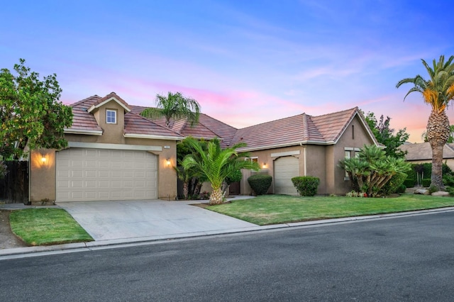 1698 E Wallington Ln, Fresno, CA 93730 - view of front of property featuring a tiled roof, stucco siding, concrete driveway, an attached garage, and a front lawn