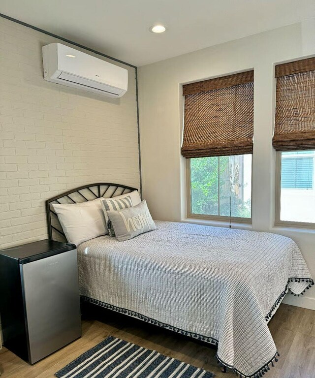 385 Fir St W, Madera, CA 93636 - bedroom with a wall mounted air conditioner, wood finished floors, freestanding refrigerator, and recessed lighting